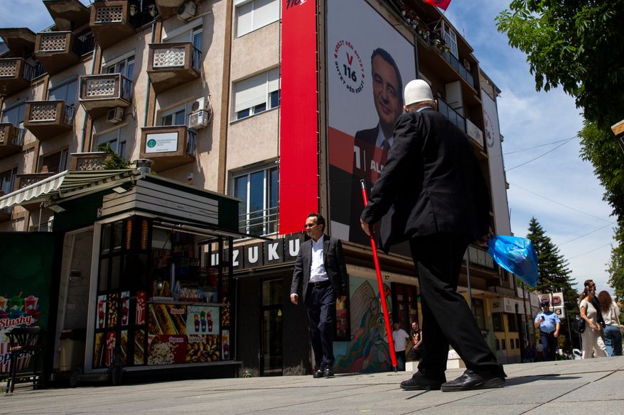 People pass by a giant election poster of acting prime minister Albin Kurti, in capital Pristina, Kosovo, Friday, June 5, 2026, ahead of snap parliamentary elections on June 7. (AP Photo/Visar Kryeziu)