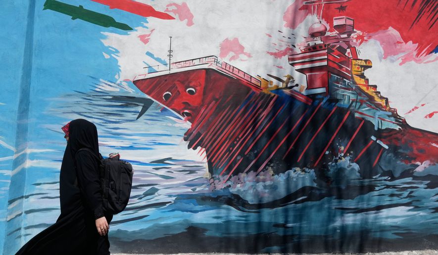 A woman walks past a mural depicting a U.S. aircraft carrier under missile attack in downtown Tehran, Iran, on Monday, June 8, 2026. (AP Photo/Vahid Salemi) **FILE**