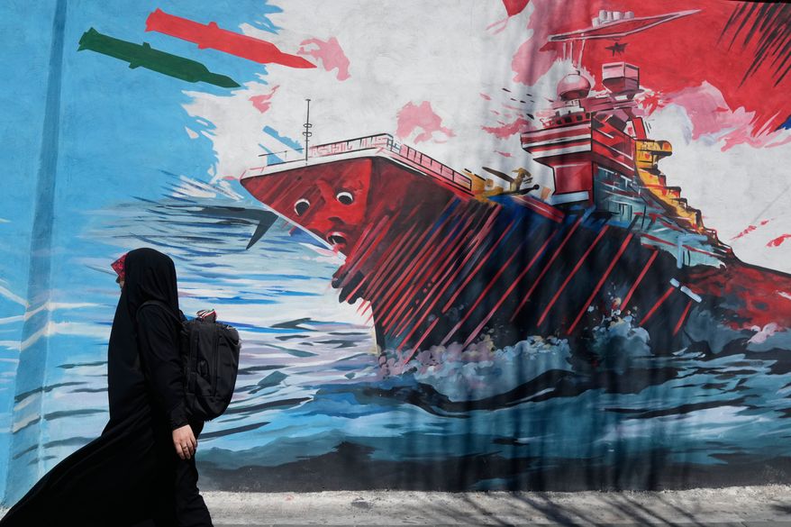 A woman walks past a mural depicting a U.S. aircraft carrier under missile attack in downtown Tehran, Iran, on Monday, June 8, 2026. (AP Photo/Vahid Salemi) **FILE**