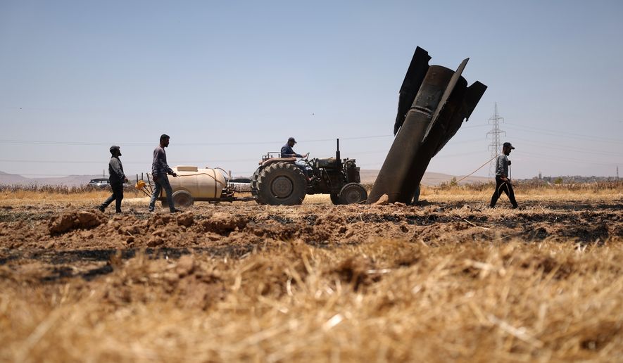 Farmers spray water in a burned agricultural field next to a projectile near the town of Najha, Syria, Monday, June 8, 2026, after debris from Iranian missile launches during the Iran-Israel conflict fell in the area. (AP Photo/Ghaith Alsayed)