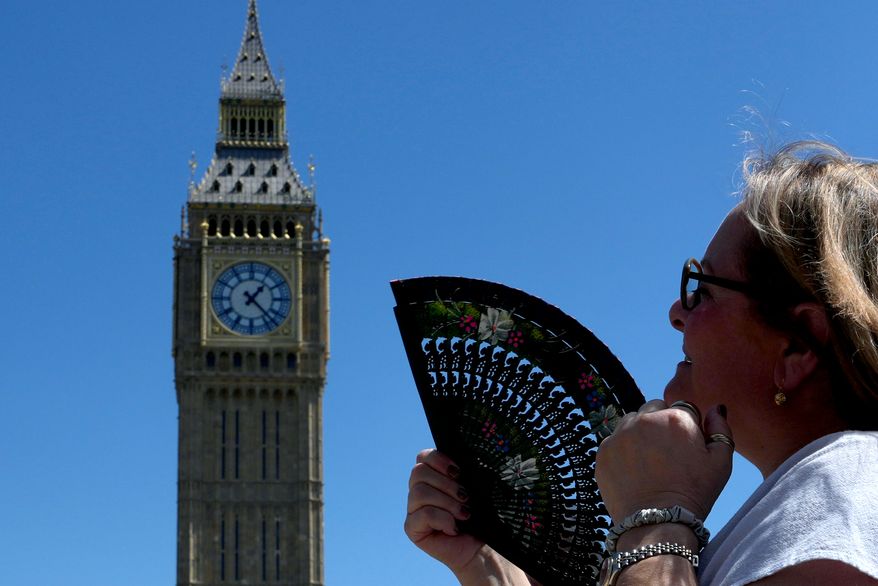 FILE - A woman cools herself outside the Palace of Westminster in London, May 26, 2026. (AP Photo/Kin Cheung, File)