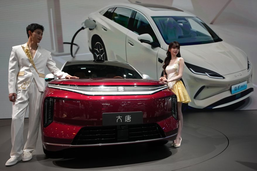 Models stand next to a latest EV car from Chinese automaker BYD showcased at the Auto China 2026, in Beijing, April 25, 2026. (AP Photo/Andy Wong, File)