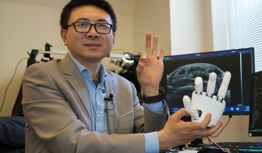 Xuanhe Zhao, professor of mechanical engineering at the Massachusetts Institute of Technology, poses for a portrait with an ultrasound wristband that can help a robotic hand mimic full hand motions in Cambridge, Mass, on Tuesday, April 14, 2026. (AP Photo/Rodrique Ngowi)