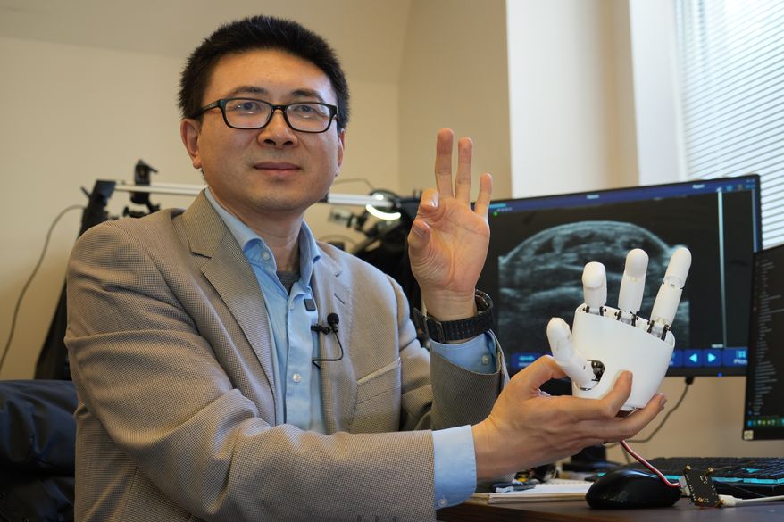 Xuanhe Zhao, professor of mechanical engineering at the Massachusetts Institute of Technology, poses for a portrait with an ultrasound wristband that can help a robotic hand mimic full hand motions in Cambridge, Mass, on Tuesday, April 14, 2026. (AP Photo/Rodrique Ngowi)