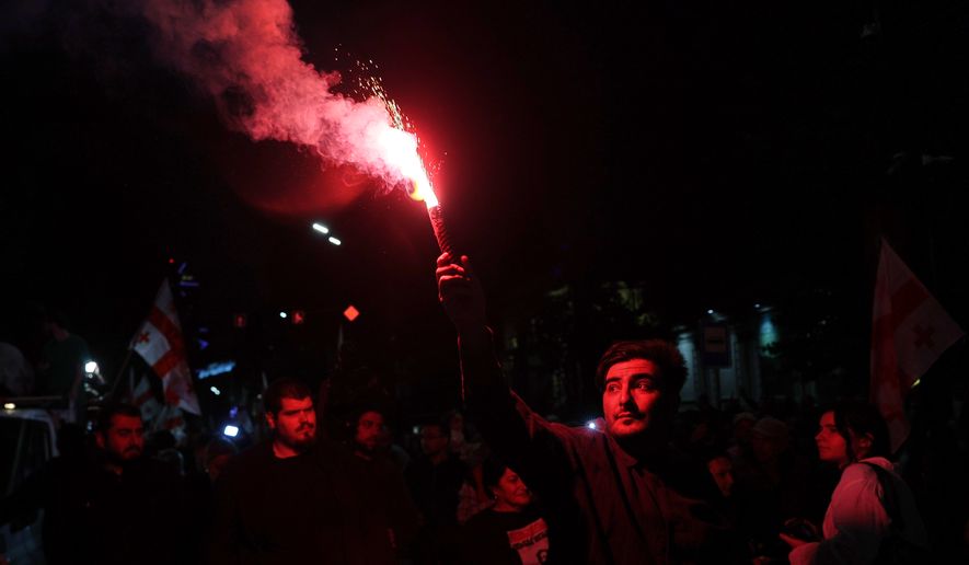 A man holds a signal flare during an opposition rally marking the Independence Day in Tbilisi, Georgia, Tuesday, May 26, 2026. (AP Photo/Zurab Tsertsvadze)