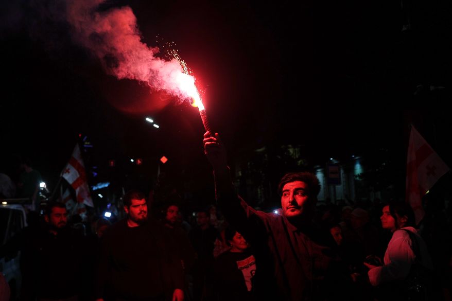 A man holds a signal flare during an opposition rally marking the Independence Day in Tbilisi, Georgia, Tuesday, May 26, 2026. (AP Photo/Zurab Tsertsvadze)