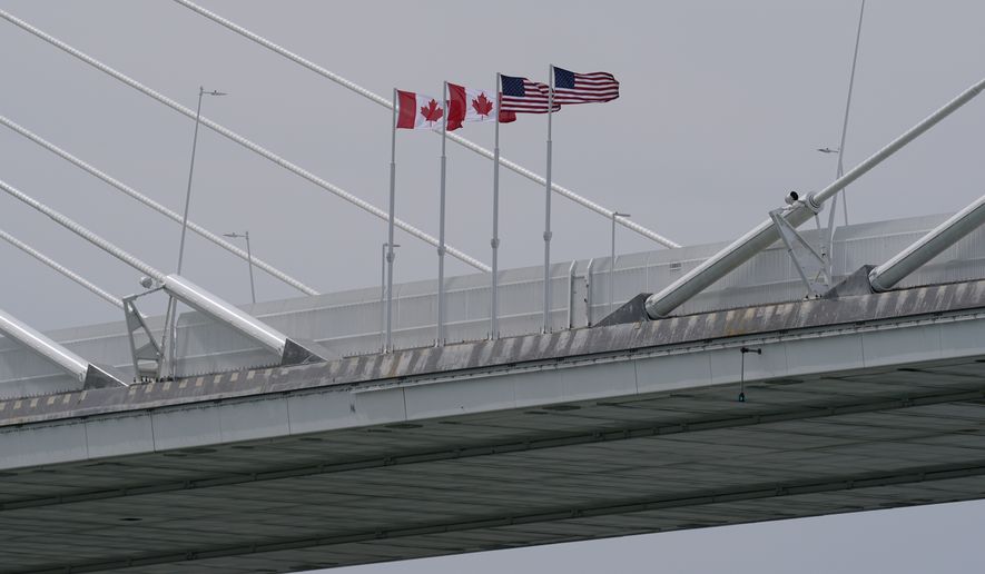 Canadian and American flags are shown on the Gordie Howe Bridge under construction between Windsor, Ontario and Detroit, May 22, 2026. (AP Photo/Paul Sancya, File)