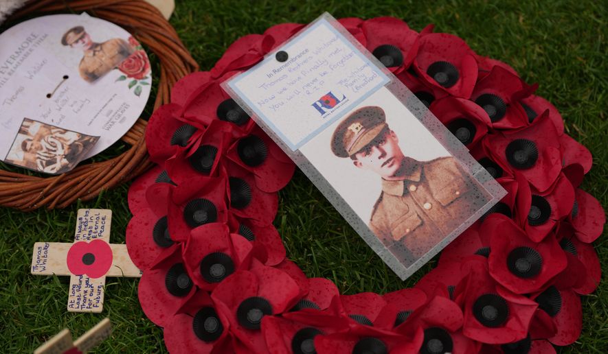 A poppy wreath and a photo next to the grave of Private Thomas Redvers Whitaker during a burial ceremony for six British soldiers of World War I, at the CWGC's Tyne Cot Cemetery in Zonnebeke, Belgium, Wednesday, June 10, 2026. (AP Photo/Virginia Mayo)