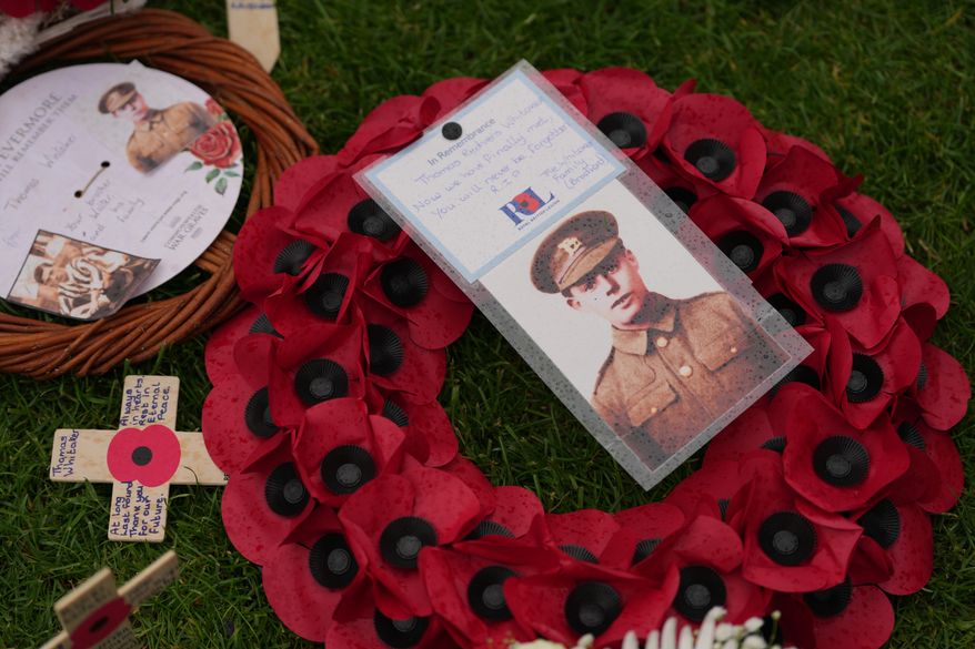 A poppy wreath and a photo next to the grave of Private Thomas Redvers Whitaker during a burial ceremony for six British soldiers of World War I, at the CWGC's Tyne Cot Cemetery in Zonnebeke, Belgium, Wednesday, June 10, 2026. (AP Photo/Virginia Mayo)