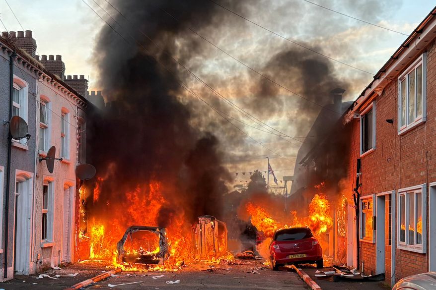 Vehicles set on fire by protesters burn on Lendrick Street in east Belfast, Northern Ireland, on Tuesday, June 9, 2026, after the arrest of a Sudanese man accused of stabbing a man in the northern part of the city. (PA via AP)