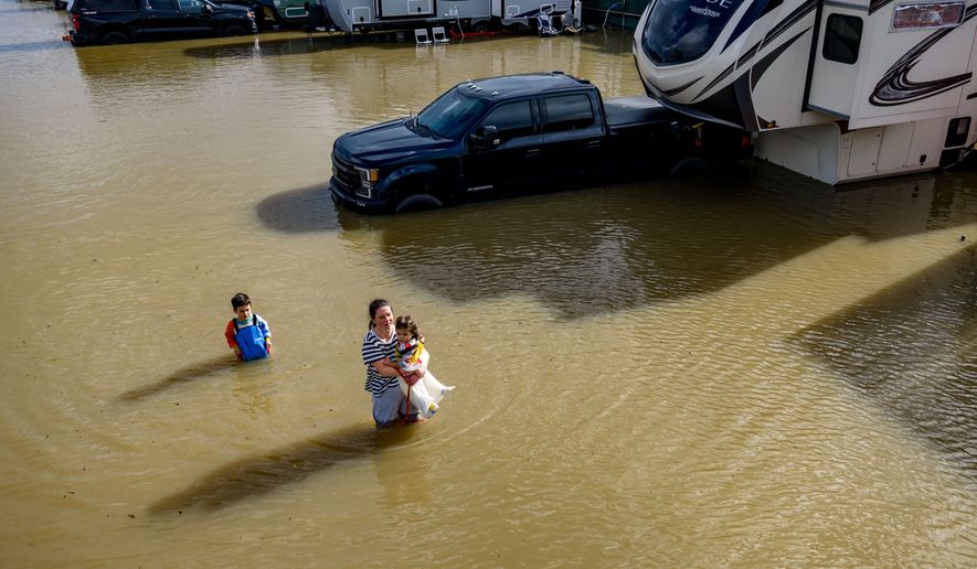 FILE - People wade through a recreational vehicle park flooded by a king tide on Jan. 3, 2026, near Corte Madera in Marin County, Calif. (AP Photo/Ethan Swope, File)