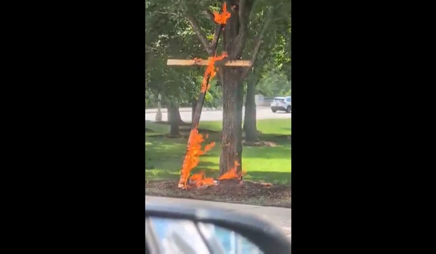 This grab from a video taken by motorist Keinika Carlton shows a wooden cross engulfed in bright orange flames as it leans against a tree in Grant Park, Chicago, Illinois, on Tuesday, July 9, 2026.(Keinika Carlton via AP)