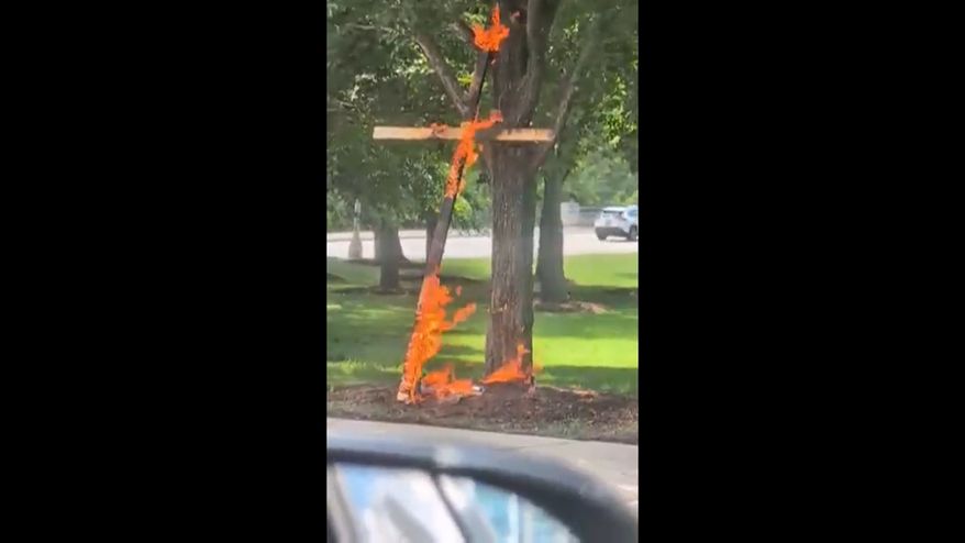 This grab from a video taken by motorist Keinika Carlton shows a wooden cross engulfed in bright orange flames as it leans against a tree in Grant Park, Chicago, Illinois, on Tuesday, July 9, 2026.(Keinika Carlton via AP)