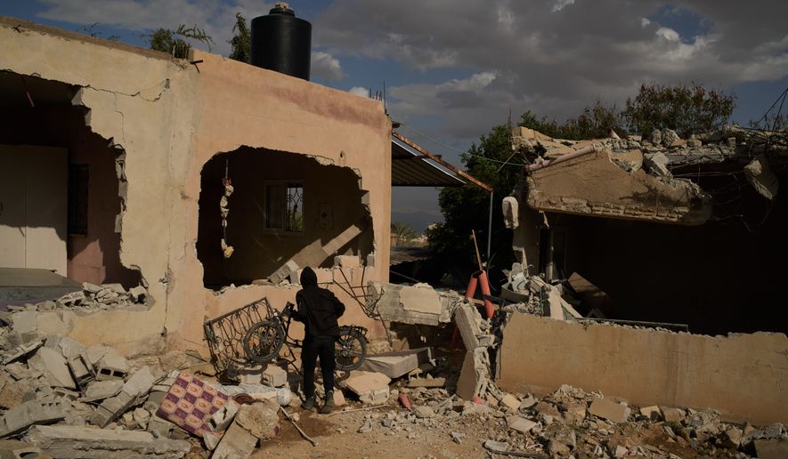 FILE -A Bedouin carries a bicycle past houses that, according to local residents, were heavily damaged yesterday during an attack by Israeli settlers in Al-Dyouk Al-Tahta area, on the outskirts of the West Bank city of Jericho, Feb. 11, 2026. (AP Photo/Leo Correa, File)