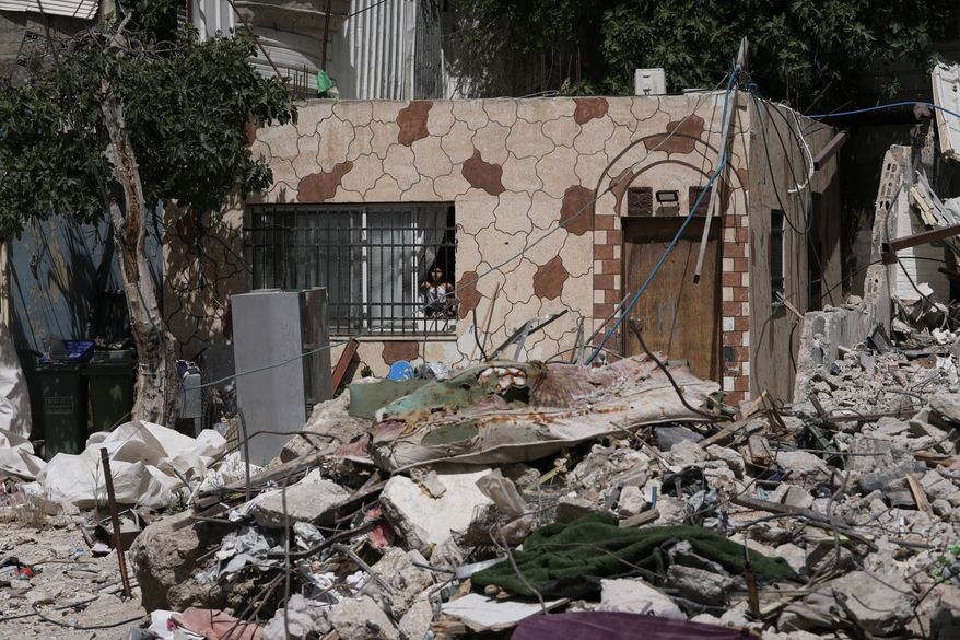 A Palestinian girl looks out a window at the rubble of a home demolished by Israeli authorities in the Silwan neighborhood of east Jerusalem, May 19, 2026. (AP Photo/Mahmoud Illean)