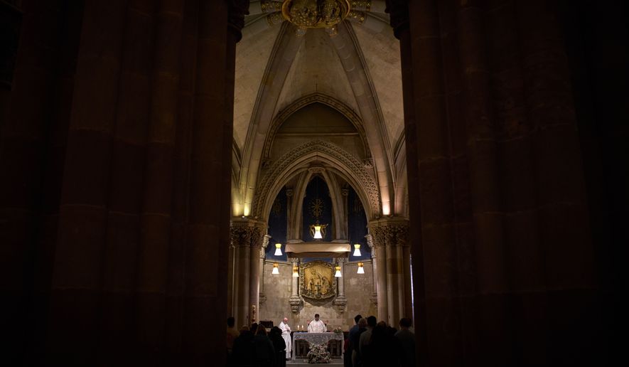 A priest celebrates Mass in the crypt of Antoni Gaudí beneath the Sagrada Familia while crowds of visitors fill the basilica above in Barcelona, Spain, May 15, 2026. (AP Photo/Emilio Morenatti)