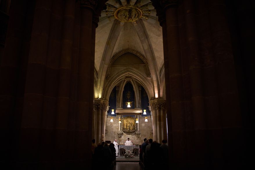 A priest celebrates Mass in the crypt of Antoni Gaudí beneath the Sagrada Familia while crowds of visitors fill the basilica above in Barcelona, Spain, May 15, 2026. (AP Photo/Emilio Morenatti)