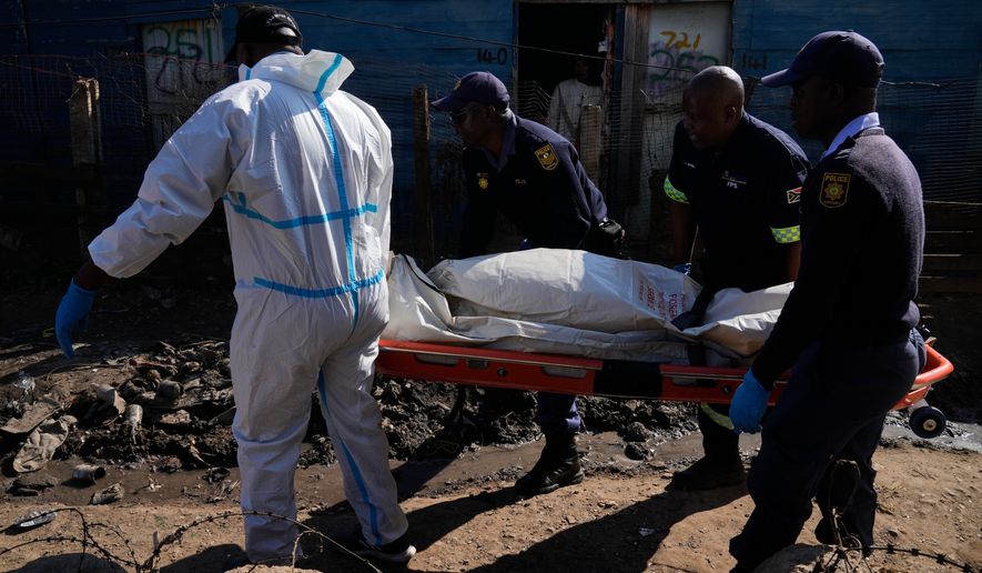 Police officers carry the body of a person on a stretcher after a mass shooting at an informal settlement in the Cleveland suburb of Johannesburg, South Africa, Wednesday, June 10, 2026. (AP Photo/Themba Hadebe)