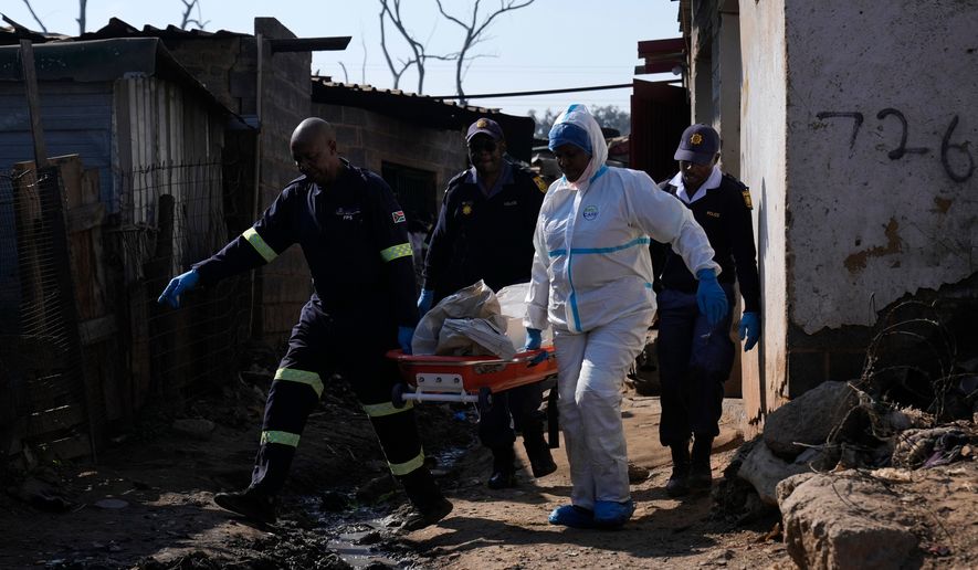 Police officers carry the body of a person on a stretcher after a mass shooting at an informal settlement in the Cleveland suburb of Johannesburg, South Africa, Wednesday, June 10, 2026. (AP Photo/Themba Hadebe)