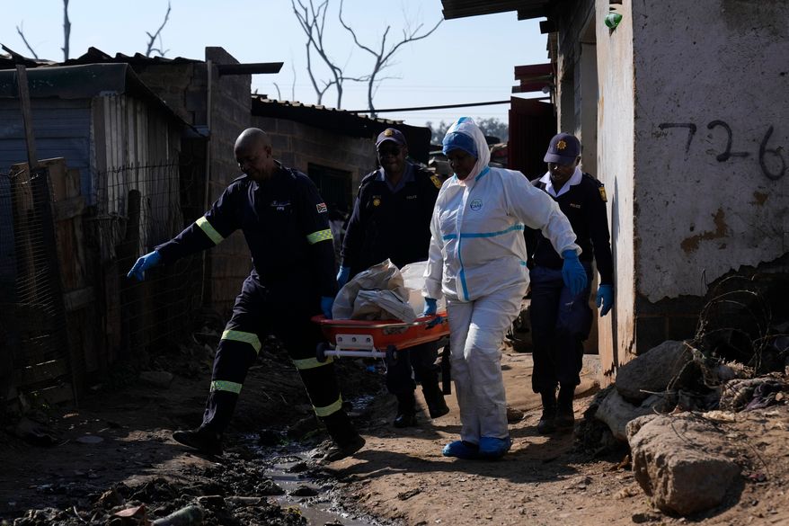 Police officers carry the body of a person on a stretcher after a mass shooting at an informal settlement in the Cleveland suburb of Johannesburg, South Africa, Wednesday, June 10, 2026. (AP Photo/Themba Hadebe)
