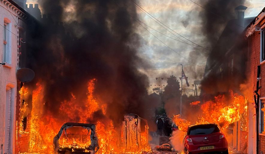 Vehicles set on fire by protesters burn on Lendrick Street in east Belfast, Northern Ireland, on Tuesday, June 9, 2026, after the arrest of a Sudanese man accused of stabbing a man in the northern part of the city. (PA via AP)