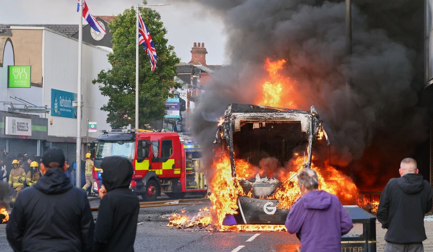 People watch as a vehicle burns during a protest in East Belfast following a stabbing incident in Belfast, Tuesday, June 9, 2026. (AP Photo/Peter Morrison)