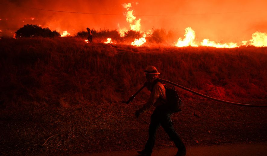 FILE - A firefighter monitors flames caused by the Hughes Fire along Castaic Lake in Castaic, Calif., Jan. 22, 2025. (AP Photo/Jae C. Hong, File)