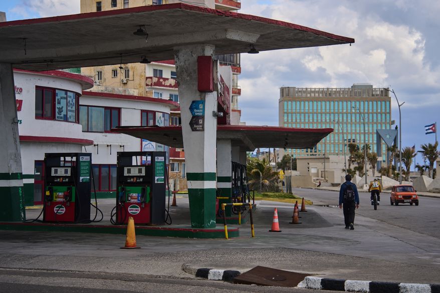 FILE - A man walks past a gas station that has run out of fuel, located near the U.S Embassy, pictured in the background, in Havana, Cuba, Feb. 7, 2026. (AP Photo/Ramon Espinosa, File)