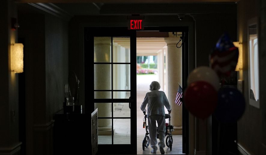 FILE - A woman uses a walker as she exits an assisted living building, July 4, 2025, in Boca Raton, Fla. (AP Photo/Rebecca Blackwell, File)