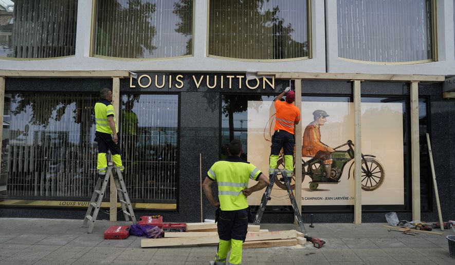 Construction workers board up a shop window, ahead of expected protests for the G7 summit, in Geneva, Switzerland, Monday, June 8, 2026. (AP Photo/Baz Ratner)