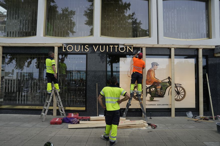 Construction workers board up a shop window, ahead of expected protests for the G7 summit, in Geneva, Switzerland, Monday, June 8, 2026. (AP Photo/Baz Ratner)