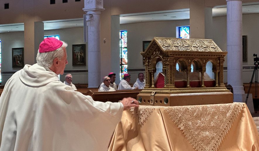 A bishop venerates relics of the 17th century St. Mary Margaret Alacoque, a French nun whose reports of visions of Jesus has led to the modern devotion of the Sacred Heart of Jesus, in front of the Basilica of the National Shrine of Mary, Queen of the Universe in Orlando, Fla., before a service Thursday, June 11, 2026, in which U.S. Catholic bishops consecrated the United States to the Sacred Heart upon the nation's 250th anniversary. (AP Photo/Peter Smith)