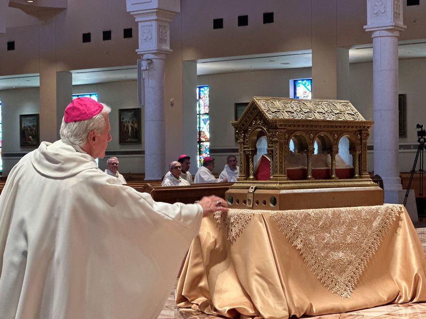 A bishop venerates relics of the 17th century St. Mary Margaret Alacoque, a French nun whose reports of visions of Jesus has led to the modern devotion of the Sacred Heart of Jesus, in front of the Basilica of the National Shrine of Mary, Queen of the Universe in Orlando, Fla., before a service Thursday, June 11, 2026, in which U.S. Catholic bishops consecrated the United States to the Sacred Heart upon the nation's 250th anniversary. (AP Photo/Peter Smith)