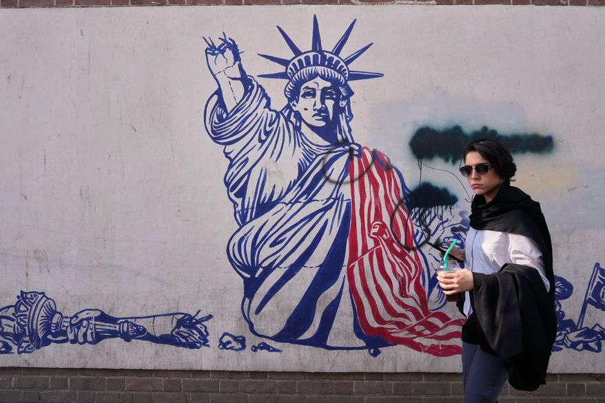 A woman walks past an anti-American mural on the wall of the former U.S. Embassy, now a museum, in Tehran, Iran, Friday, June 12, 2026. (AP Photo/Vahid Salemi)