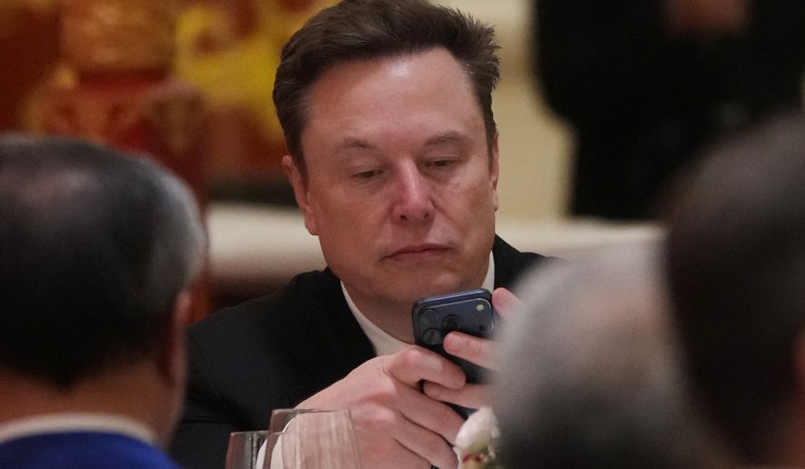 FILE - Elon Musk uses his phone during a state dinner for President Donald Trump and Chinese President Xi Jinping at the Great Hall of the People on Thursday May 14, 2026, in Beijing. (AP Photo/Mark Schiefelbein, File)