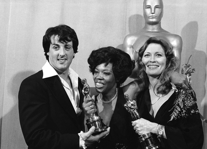 Actor and screenwriter Sylvester Stallone, left, poses with Eletha Finch, center, widow of actor Peter Finch, and actress Faye Dunaway at the Academy Awards in Los Angeles on March 28, 1977. (AP Photo/File)