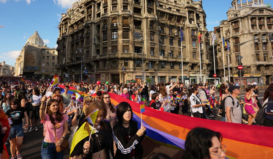 People walk carrying a rainbow flag during the Bucharest Pride Parade, in Bucharest, Romania, Saturday, June 13, 2026. (AP Photo/Andreea Alexandru)