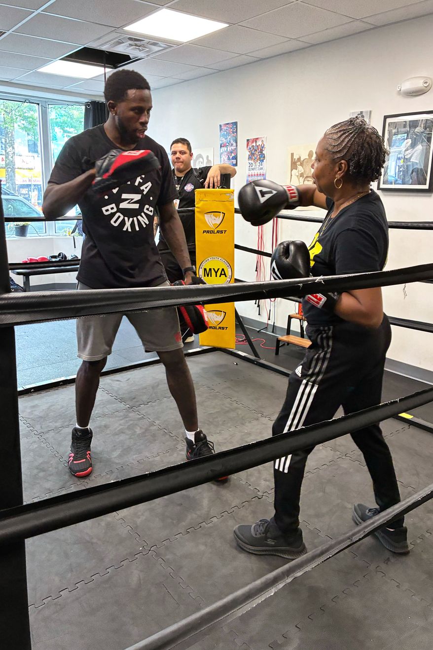 Midtown Youth Academy Executive Director Gloria Lee spars with UFC fighter Randy Brown at an event Wednesday, June 10, 2026, in Washington. (AP Photo/Fatima Hussein)