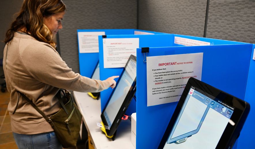 FILE- Courtney Parker votes on a new voting machine, in Dallas, Ga., Nov. 5, 2019. (AP Photo/Mike Stewart, File)