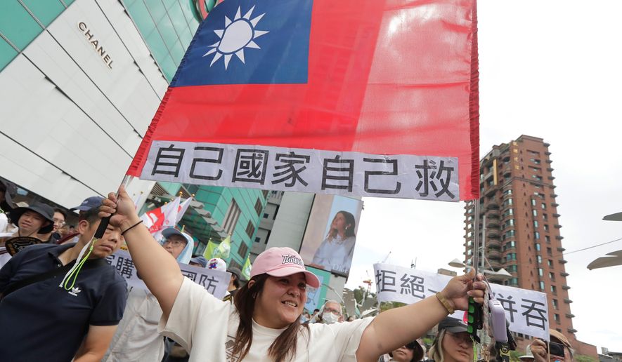 A woman holds up Taiwan's flag with a slogan reading, "Save our own country!" in Taipei, Taiwan, Saturday, May 23, 2026. (AP Photo/Chiang Ying-ying)