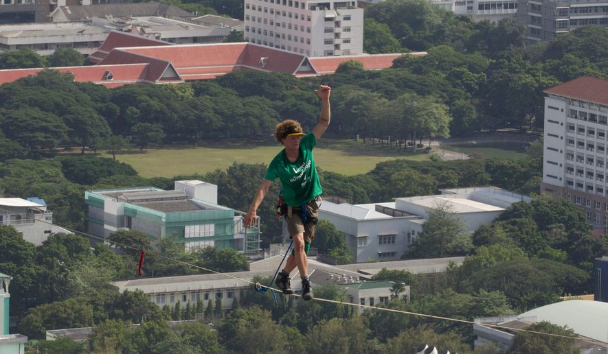 U.S. slackliner Andy Lewis of Calif. balances on a slackline in Bangkok, Thailand, July 23, 2014. (AP Photo/Sakchai Lalit, File)