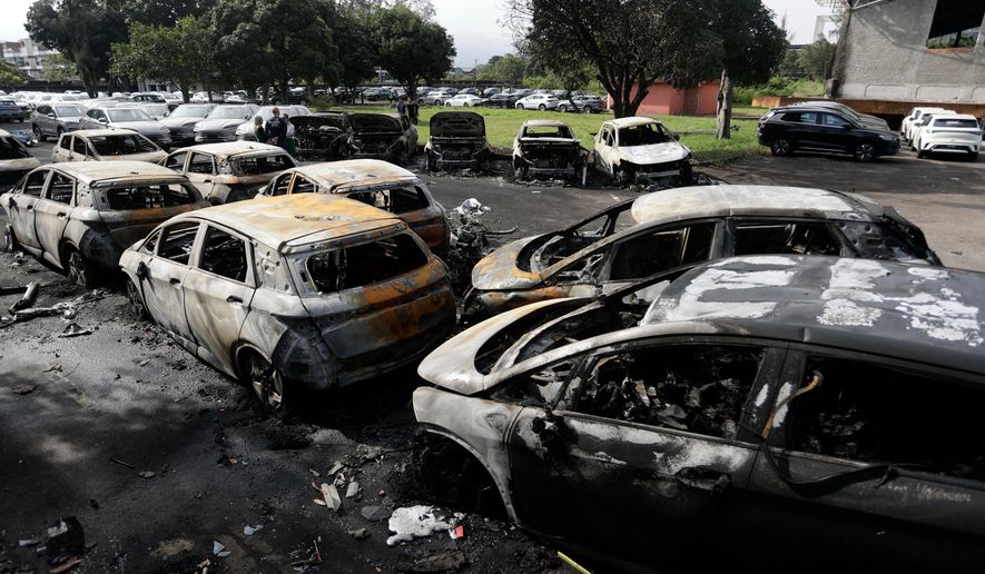 Burned vehicles fill a car dealership parking lot where, according to police, two helicopters collided in midair and crashed in Rio de Janeiro, Brazil, Sunday, June 14, 2026. (AP Photo/Bruna Prado)