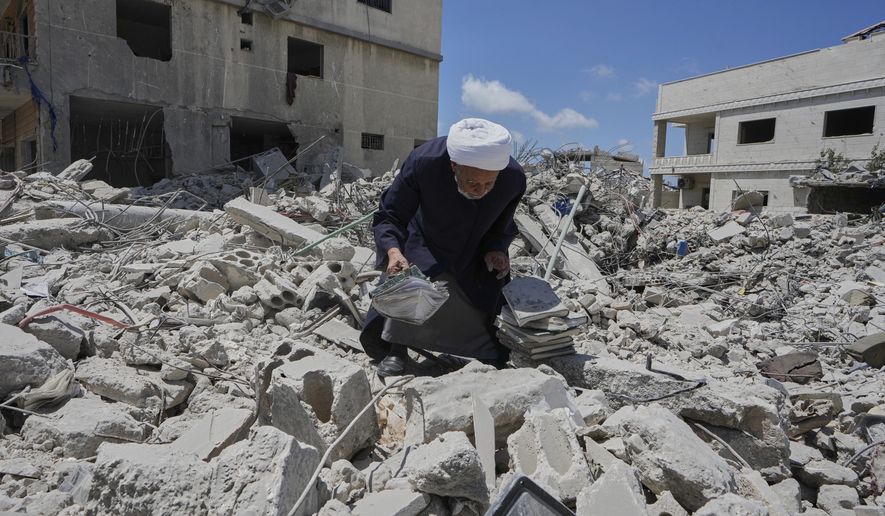 A Shiite sheikh who returns to his village following the announcement of an initial ceasefire agreement between the United States and Iran, collects religious books from his destroyed library in Deir Qanoun, south Lebanon, Monday, June 15, 2026. (AP Photo/Mohammed Zaatari)