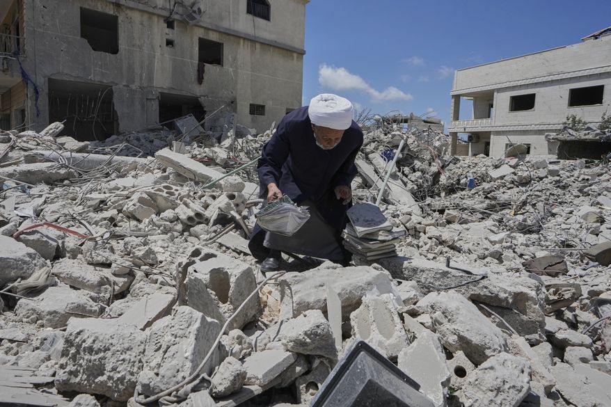 A Shiite sheikh who returns to his village following the announcement of an initial ceasefire agreement between the United States and Iran, collects religious books from his destroyed library in Deir Qanoun, south Lebanon, Monday, June 15, 2026. (AP Photo/Mohammed Zaatari)