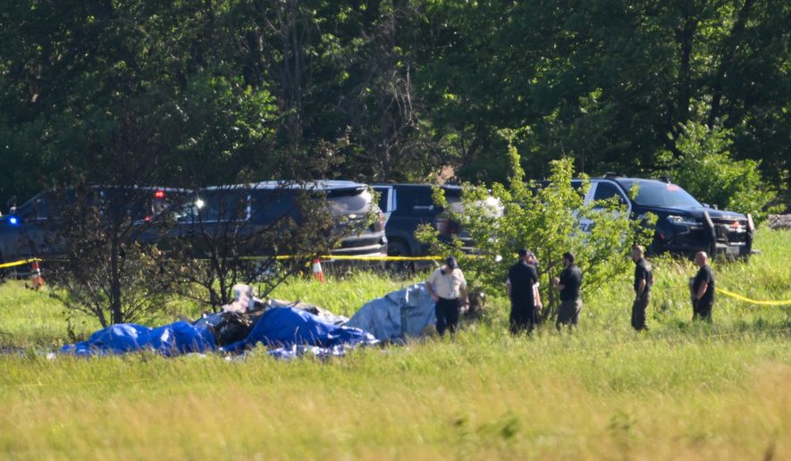 Emergency personnel investigate the site of a plane crash at the Butler Memorial Airport in Butler, Mo., Sunday, June 14, 2026. (AP Photo/Reed Hoffmann)