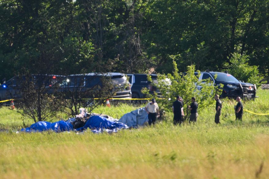 Emergency personnel investigate the site of a plane crash at the Butler Memorial Airport in Butler, Mo., Sunday, June 14, 2026. (AP Photo/Reed Hoffmann)