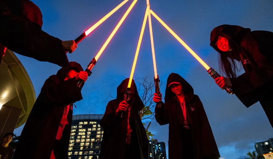 Star Wars fans dressed in costumes hold lightsabers during a themed night run in Hong Kong, Friday, May 1, 2026. (AP Photo/Chan Long Hei)