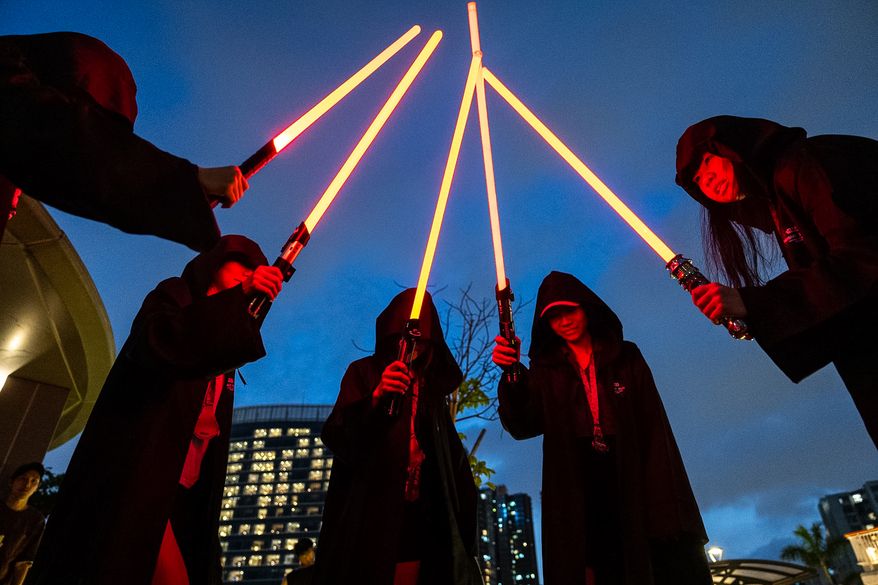 Star Wars fans dressed in costumes hold lightsabers during a themed night run in Hong Kong, Friday, May 1, 2026. (AP Photo/Chan Long Hei)