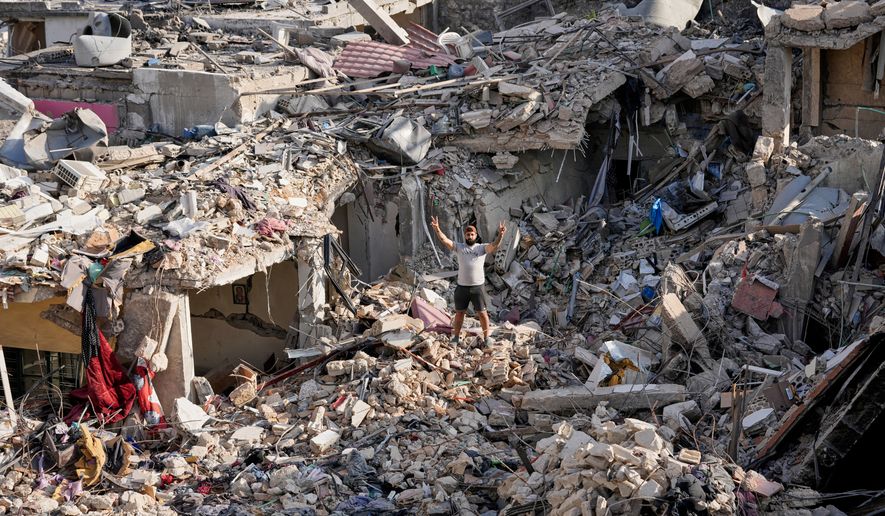 A man who returns to his village following the announcement of an initial ceasefire agreement between the United States and Iran, flashes victory sign as he stands on the rubble of his destroyed house in Nabatiyeh town, southern Lebanon, Tuesday, June 16, 2026. (AP Photo/Hussein Malla)
