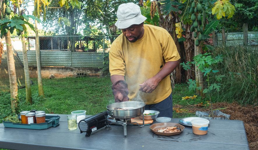 Rashad Frazier prepares food outdoors in Lava Lands, Ore., on Aug. 7, 2024. (Alex Forestier via AP)